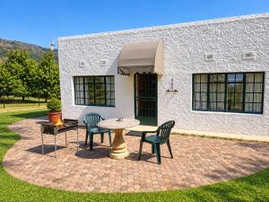 a patio with two chairs and a table and a grill at Nut Tree Nook in Hazyview