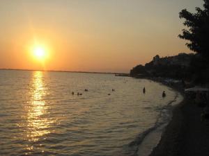 a group of people swimming in the ocean at sunset at Panorama in Menídion +2 photos