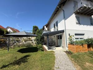 a white house with an umbrella in the yard at Ferienwohnung Auszeit in Niederviehbach