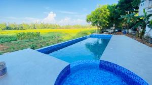 a blue swimming pool with a view of a field at Owin Rose Yala Safari Hotel in Tissamaharama