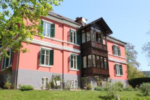 a pink house with a cat on the roof at Villa Adrienne in Velden am Wörthersee