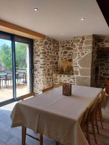 a dining room with a table and a stone wall at Gîte Le Valeix in Neuvic