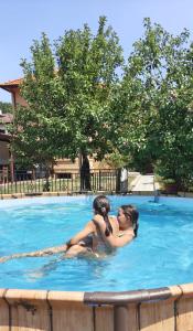 two women sitting in a swimming pool at Gaga Martinovo - Mountain House - Sauna & Pool in Martinovo