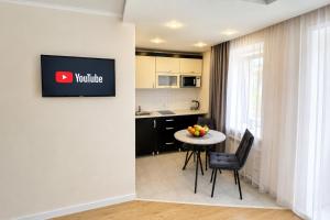 a room with a kitchen with a table and a tv on a wall at Габдуллина 79 in Kokshetau