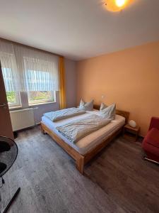 a bedroom with a bed and a red chair at Hotel & Gasthaus Forelle in Thale