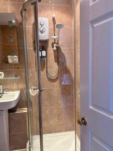 a shower with a glass door next to a sink at Stopover Stoford in Stoford