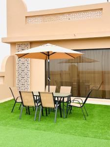 a table and chairs with an umbrella on the grass at Britstar Suites Salalah in Salalah