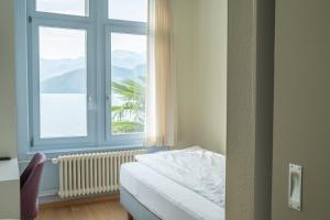 a bedroom with a bed and a large window at Seminar-Hotel Rigi am See in Weggis +14 photos