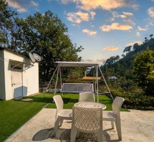 a patio with a table and chairs and a swing at Heera Lodge Kasauli By Evening Sky Hotel in Kasauli
