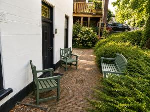 three green benches sitting outside of a house at Cozy apartment in authentic farmhouse in Gouda