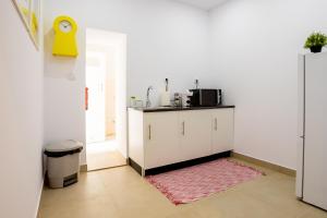 a kitchen with white cabinets and a pink rug at Sleep in Centre - Old Town in Aveiro +52 photos