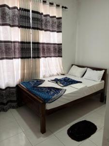a bed in front of a window with a curtain at Royal place in Mahiyangana