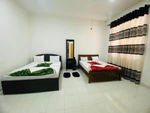 a room with two beds and a chair in it at Royal place in Mahiyangana