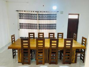a wooden dining room table with chairs and a curtain at Royal place in Mahiyangana
