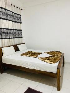 a bed with white sheets and a blanket on it at Royal place in Mahiyangana