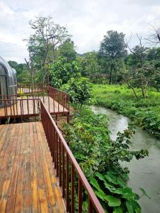 a wooden deck with a river next to a train at SKYLINE vangvieng Resort in Vang Vieng