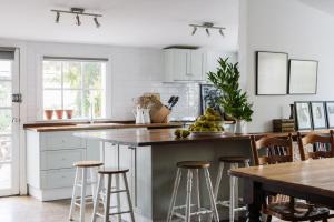 a kitchen with white cabinets and a counter with bar stools at Piccadilly House Daylesford in Daylesford