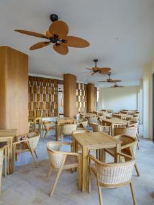 a restaurant with wooden tables and chairs and bookshelves at Kinan Sentral in Fulidhoo