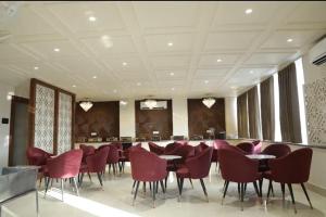 a restaurant with red chairs and tables and a bar at La Falcon Hotel in Rohtak