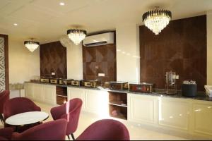 a kitchen with a counter with chairs and a table at La Falcon Hotel in Rohtak