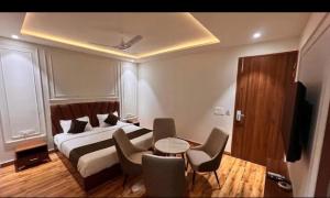 a bedroom with a bed and a table and chairs at La Falcon Hotel in Rohtak