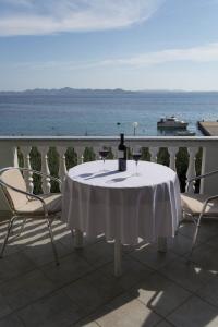 a table with wine glasses on a balcony with the ocean at Apartments Jurjevic in Petrcane