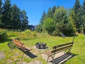 two park benches sitting next to a fire pit at Pensjonat i domki Kresy in Pogorzelce