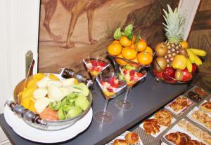 a table topped with bowls of fruit and wine glasses at Hôtel La Tour Perrier in Eyrans-de Soudiac