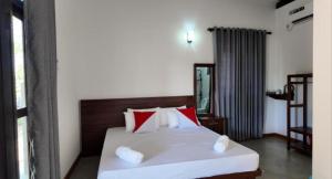 a bedroom with a bed with red and white pillows at wild elephant reach wilpaththuwa in Nochchiyagama
