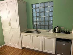 a kitchen with white cabinets and a sink and a window at Tinian diamond hotel in Tinian International Airport