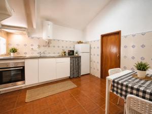 a kitchen with white cabinets and a table and a refrigerator at Casa do Botelho in Évora