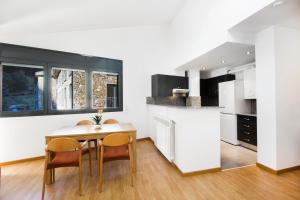 a kitchen with a table and two chairs and a counter at Font del Ferro Apartments in El Tarter
