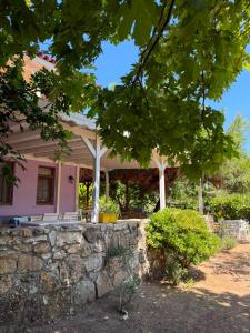 ein rosafarbenes Haus mit einer Steinmauer und Bäumen in der Unterkunft Nar Bağevi in Bozcaada