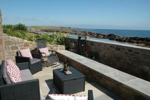 a patio with chairs and a table and the ocean at The Coopers View in Cellardyke