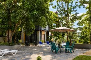 a patio with chairs and a table and an umbrella at TUNA Hiriketiya - Luxury Resort & Pool Retreat in Hiriketiya