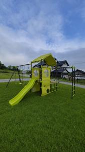 a playground with a yellow slide in the grass at Domek na Ogrodowej in Tylicz