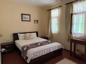 ein Schlafzimmer mit einem Bett und zwei Fenstern in der Unterkunft Nar Bağevi in Bozcaada