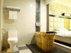 a bathroom with a toilet and a wooden basket at Behito Hotel in Dongguan