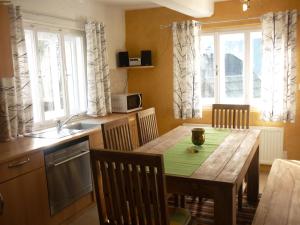 eine Küche mit einem Holztisch mit Stühlen und eine Küche mit Fenstern in der Unterkunft Ferienhaus Maria in Patergassen