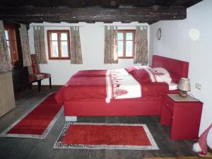 ein Schlafzimmer mit einem roten Bett in einem Zimmer mit Fenstern in der Unterkunft Ferienhaus Maria in Patergassen