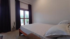 a bedroom with a bed and a large window at villa calm haven in Unawatuna