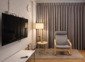 a living room with a chair and a flat screen tv at Into the town krabi in Krabi