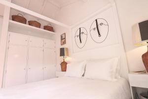 a white bedroom with two faces on the wall at Senhora do Cabo Meco Homy Holidays in Sesimbra