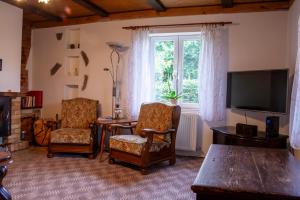 a living room with two chairs and a table and a television at Chalupa Na Žofíně in Horní Podluží