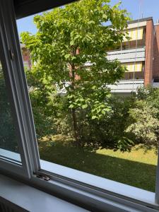 a window view of a tree and a building at Zurich Cozy Room in Zumikon