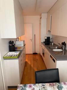 a small kitchen with white cabinets and a sink at Zurich Cozy Room in Zumikon +2 photos