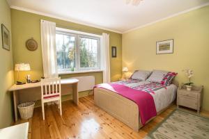 a bedroom with a bed and a desk and a window at Biała Przystań in Sasino