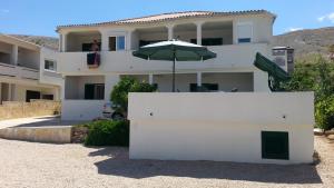 a white building with an umbrella in front of it at Apartments Feniks in Pag