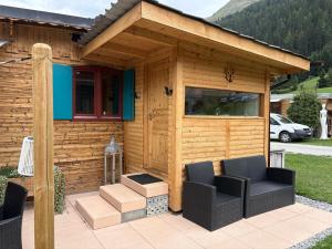 a wooden cabin with two chairs and a grill at Mobile home Le paradis dans la nature in Bourg-Saint-Pierre