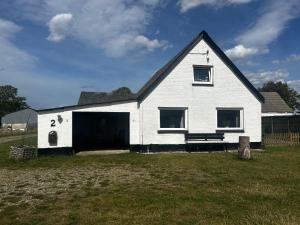 a white house with a black roof and a yard at Small house in rural surroundings in Gelstrup